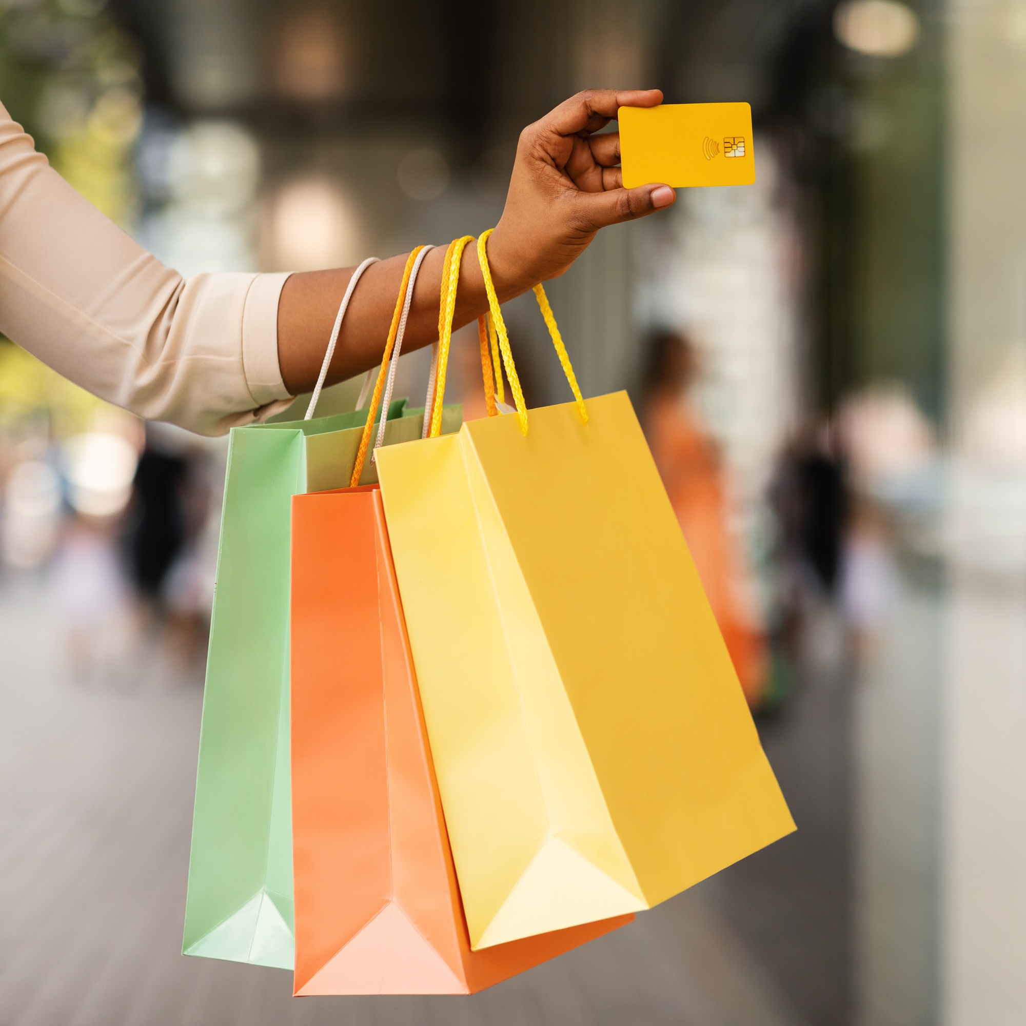 Unrecognizable black consumer holding credit card and shopping bags
